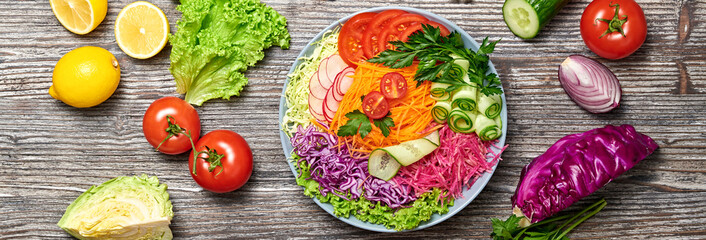 Rainbow salad with tomato, lettuce, cucumber, red cabbage, carrot, radish. Paleo diet, healthy vegan and balanced food concept. Fresh mix green leaves homemade vegetable salad on wood, banner