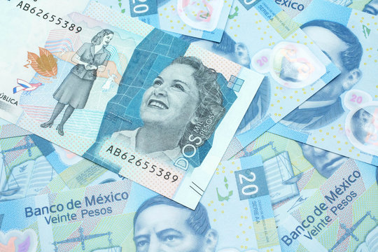 A close up image of a blue two thousand Colombian peso bank note on a background of Mexican twenty peso bank notes in macro