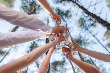 Friends Cheers. Hands with glasses of wine toasted, bottom view. Celebration, Success, Friends. Group of partying friends clinking flutes, close up. Flat lay Celebrate.