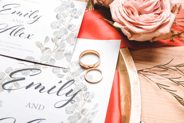 Beautiful wedding invitations with rings on table, closeup