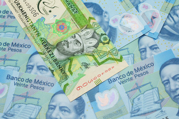 A one manat bank note from Turkmenistan close up in macro with an assortment of Mexican twenty peso bank notes.
