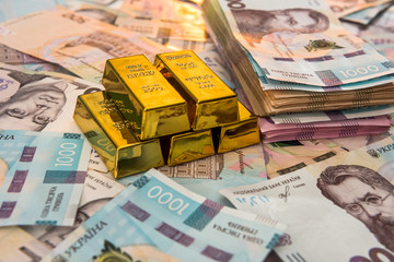 Top view of gold bars lying on a background of Ukrainian money. UAH. Save and money concept