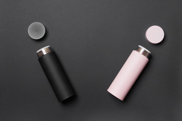 black and pink thermos cup on black colored paper background
