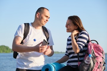 Talking man and woman 40 years old, looking at smartphone