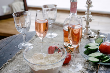 Pink champagne with flour cucumbers and tomatoes on a wooden table