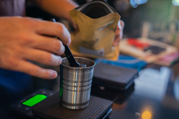 Attractive Asian barista the coffee shop owner preparing coffee for his customer. Film tone effected. Close-up and selective focused
