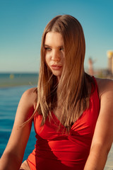 Fashionable woman in red bikini sitting near the pool