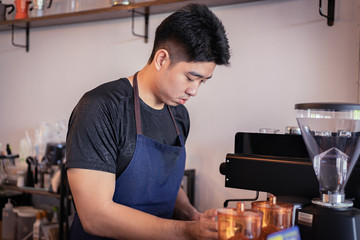 Attractive Asian barista the coffee shop owner preparing coffee for his customer. Film tone effected