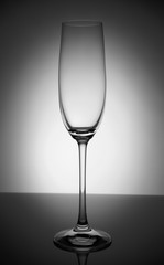 Empty champagne glass with reflection, on white and black gradient background. Concept, party and club life. Magazine and commercial photo with place for text or design, festival and holiday food and