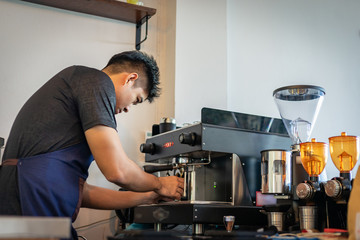 Attractive Asian barista the coffee shop owner preparing coffee for his customer. Film tone effected