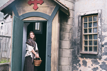 Woman in retro dress in the courtyard of an old Church with a cross above the door, clothes on Halloween