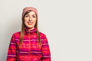 Friendly emotional Young woman in a hat and a pink sports jacket with a smile on a white background with copy space. Concept modern trendy style. Face expression. Banner