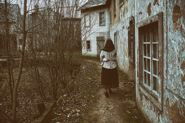 A girl in an ancient dress leaves the path with a scarf draped over her head. Woman on a background...