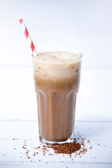 Ice coffee or caffe latte in a tall glass  with coffee beans on a wood white background, Selective focus, copy space, Summer drink iced coffee.