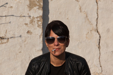 Obraz premium beautiful young girl photographed in black leather jacket with sunglasses and cigarette