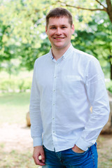 Portrait of young man standing at park and smiling