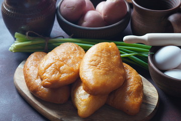 Russian Patties (Pasties, Hot Cakes, Pirozhki, Pies) on wooden cupboard . Traditional homemade fried pies with potatoes