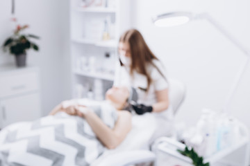 blurred photo of a spa where a doctor performs a procedure on a woman lying on the bed. Copy space