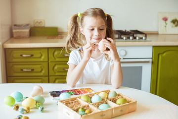 Little girl having fun to paint easter eggs