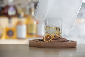 Hazy Whiskey Cocktail, A glass of smoked whiskey served with a slice of dry orange and cinamon...