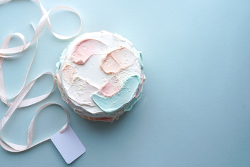 Birthday holiday cake with and pink ribbon with card on blue background. Photo