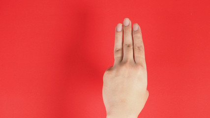 Naklejka premium A hand sign of 3 fingers point upward meaning three, third or use in protest.It put on red background
