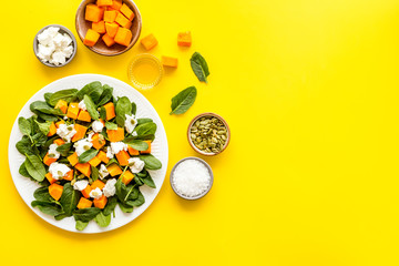 Salad with pumpkin and basil - near ingredients - on yellow background top-down copy space