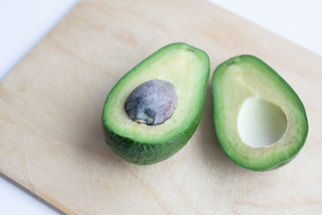 Ripe avocado, cut into two halves, on a wooden board