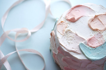 Holiday cake with and pink ribbon on blue blurred background. Photo