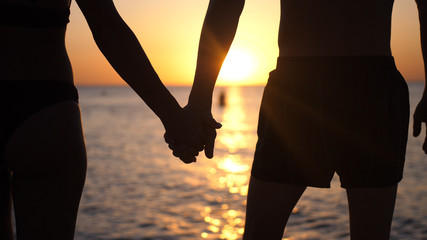 Couple holding hands each other and walking at sunset