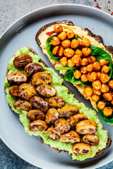 Vegan toasts with guacamole and mushrooms, hummus with chickpeas on rye bread, top view. Healthy vegan food concept.