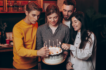 friends light candles on a cake made for their girlfriend's birthday