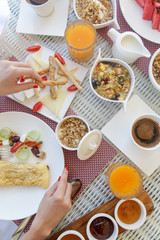 Beautifully arranged breakfast table with coffee, orange juice, pastry, fruits, cereals and eggs, top view	