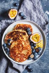 Oatmeal pancakes with honey, fruits and berries, blue background, top view. Healthy vegan food concept.