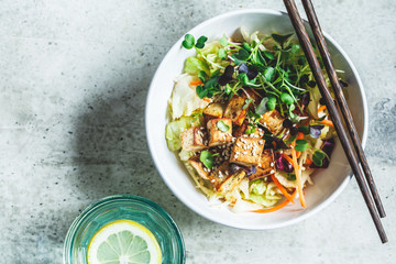 Fried tofu salad with sprouts and sesame seeds in white bowl, top view. Vegan food, asian food...