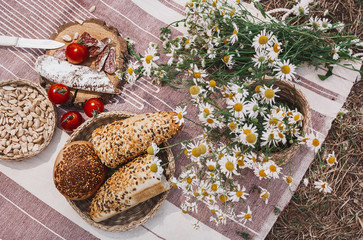 picnic in boho style. plaid on which lies a picnic food, sausages, nuts, red tomatoes and fresh...