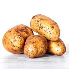 some new brown potatoes on a white wooden table