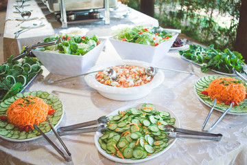 salad table with arugula, cucumber, carrot and vinaigrette