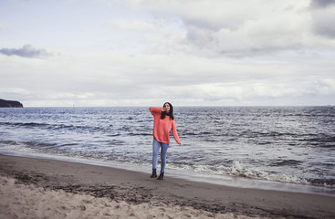 happy young woman walking in casual clothes on the shore of sea