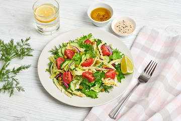Fresh salad with cherry tomatoes, savoy cabbage, cucumeber on dish. Healthy summer salad vegetarian meal concept. Tasty mixed leaves, tomatoes and mix vegetable salad on white wood