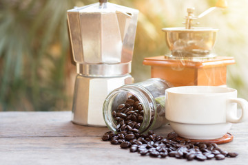 A cup of hot espresso coffee mugs and roasted coffee beans with moka pot placed on wooden floor background,coffee morning,selective focus