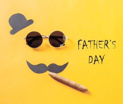 Father's day concept. Hipster sunglasses and funny moustache with hat and cigar on yellow background.flat lay, top view.