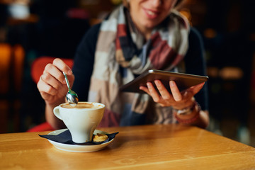 Beautiful Caucasian woman with coffee looking at her tablet	