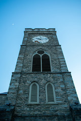 Fototapeta na wymiar A Clock Tower on a Cobblestone Tower in a Blue Sky