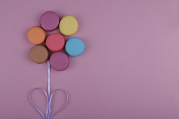  colored french macaroons in the form of a flower on a pink background