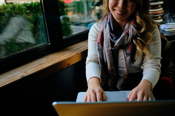 Beautiful Asian woman with laptop sitting in a cafe and smiling	