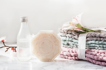 Fototapeta na wymiar natural soap. handmade soap with a bottle of oil. Stack of fresh towels with flowers on a white background. spa treatments.