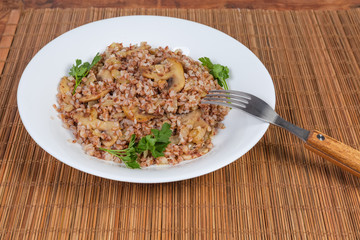 Buckwheat porridge with fried mushrooms and onions on dish, fork