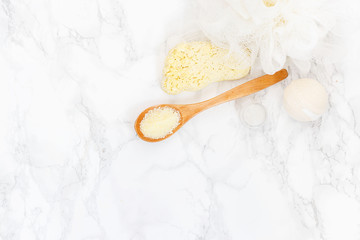sea salt in a wooden spoon, washcloth, pumice for feet on a white background. yellow bathing salt...