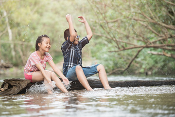 happy group little asian girl and boy child having fun to playing in the river in summer time with smile and laughing healthy, smiling face adorable. Summer camp for kids. vacation lifestyle concept.